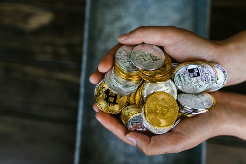 Cupped hands holding a pile of Bitcoin coins representing an exchange deposit amount