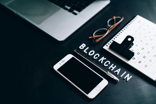 Laptop and phone on a desk with blockchain-related notes representing a converter estimate workflow