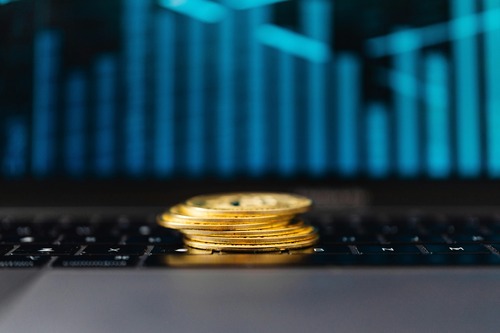 Stack of Bitcoin coins on a laptop keyboard with a price chart in the background